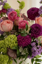 IN𝓃 Floral Studio Blush Atelier arrangement with pink roses, purple dahlias, green hydrangeas, and purple stock in a white vase.