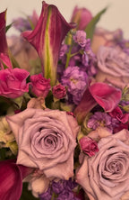 IN𝓃 Floral Studio Blush Calla arrangement with pink roses, purple calla lilies, tulips, stock, hydrangeas, and greens in a vase.