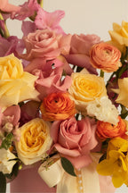 IN𝓃 Floral Studio pastel garden arrangement with blush pink and yellow roses, ranunculus, and gladiolus in a pink hat box.
