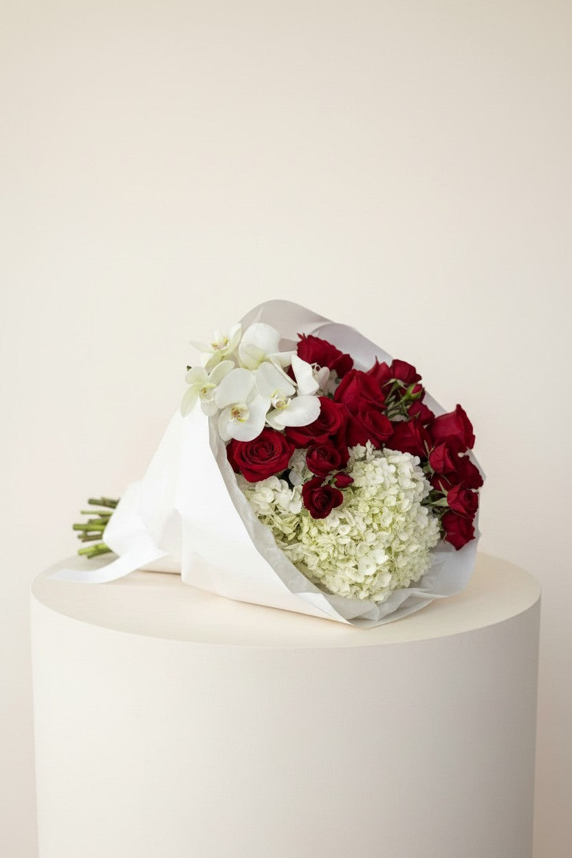 IN𝓃 Floral Studio red roses, white orchids, and hydrangeas bouquet in white paper wrap with ribbon.