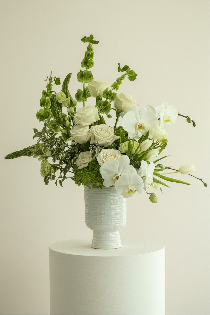 IN Floral Studio Soft White Garden arrangement with ivory roses, white orchids, and green accents in a textured ceramic vase.