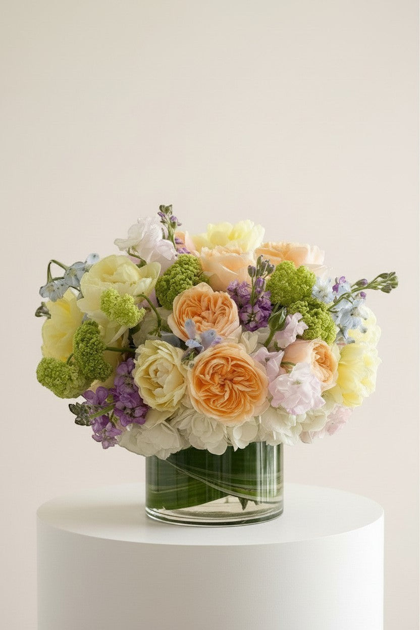 IN𝓃 Floral Studio Spring Garden Deluxe arrangement with roses, tulips, delphiniums, viburnum, stock, sweet peas, and hydrangeas in a glass vase.