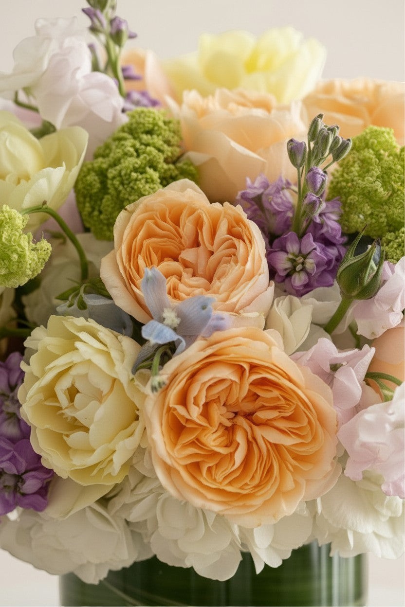 IN𝓃 Floral Studio Spring Garden Deluxe arrangement with roses, tulips, delphiniums, viburnum, stock, sweet peas, and hydrangeas in a glass vase.