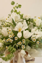 IN𝓃 Floral Studio White Meadow arrangement: white tulips, chamomile, carnations, molucella, ranunculus butterfly, and greens in a woven basket with ribbons.