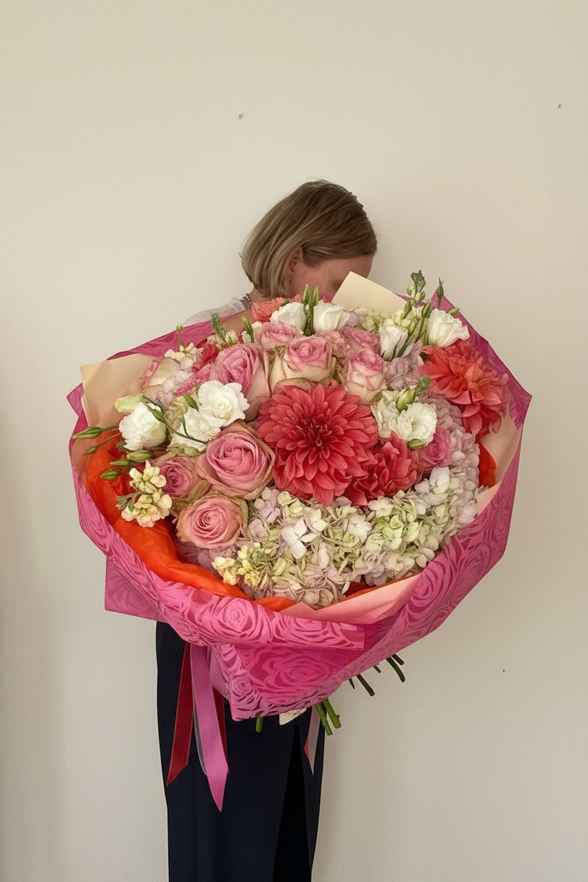IN𝓃 Floral Studio large garden bouquet with coral dahlias, blush roses, and hydrangeas wrapped in pink paper.